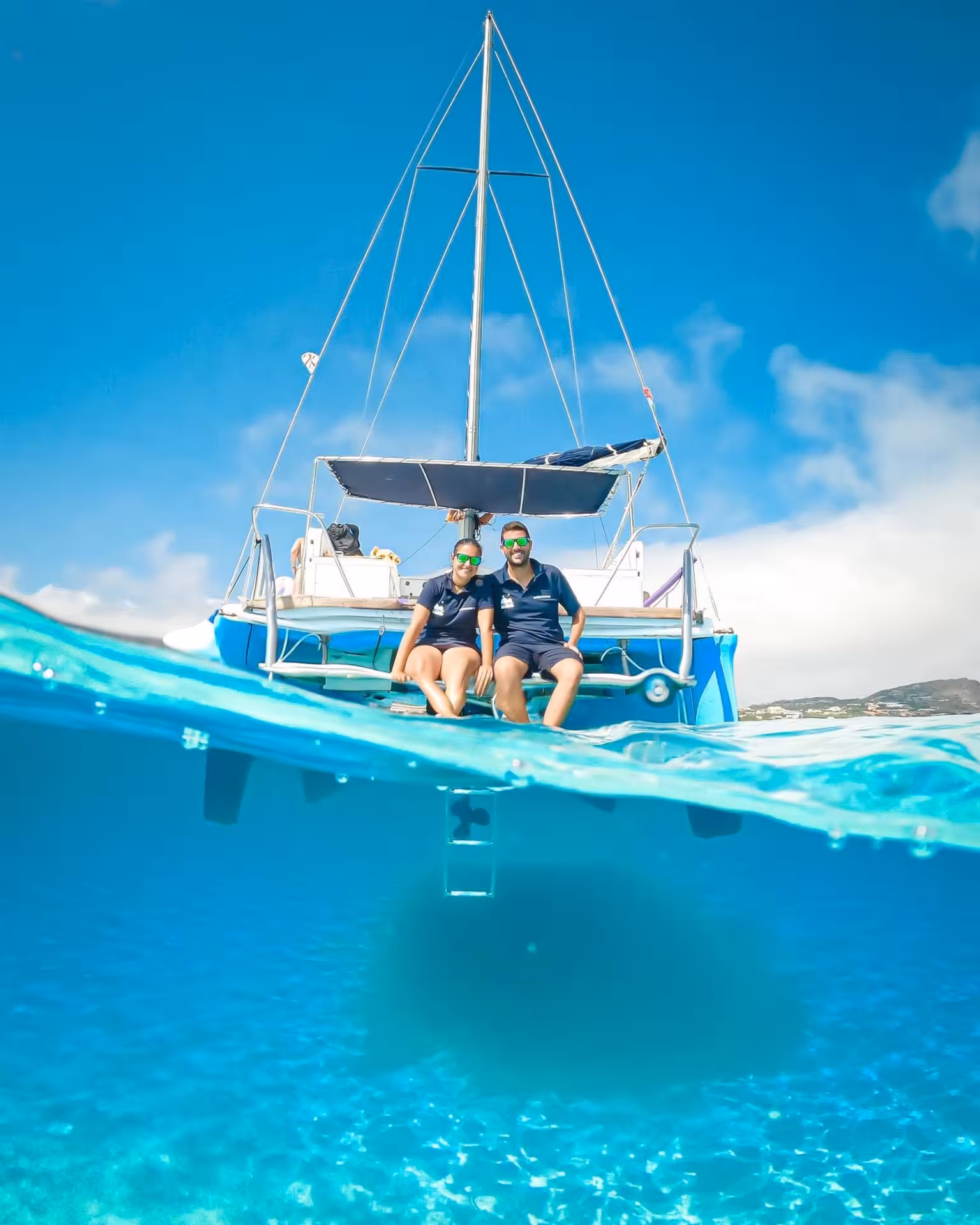 Two people relaxing on a catamaran in the clear blue waters of the Gulf of Asinara near Stintino, perfect for a scenic trip.