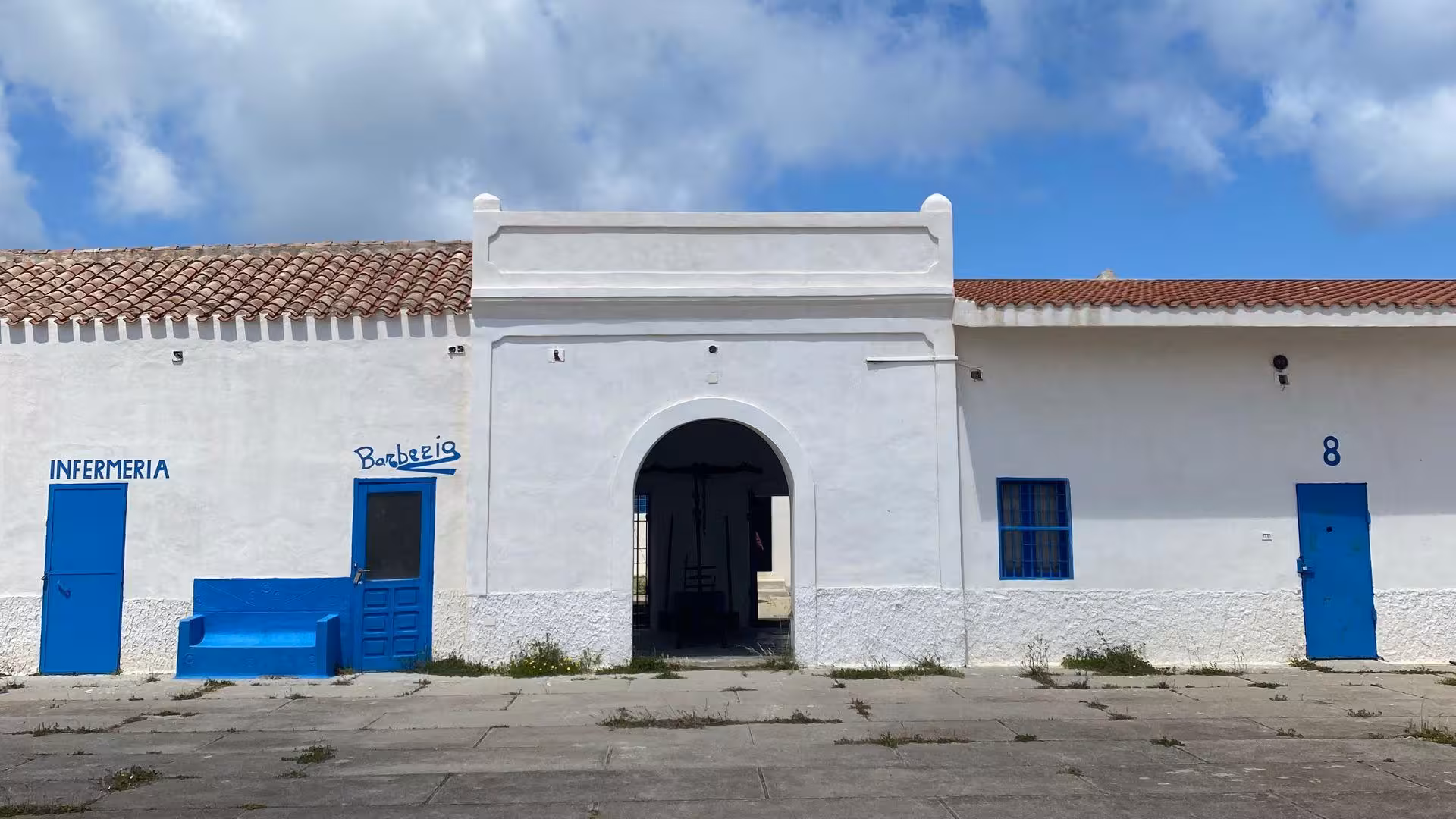 White building with blue accents on Asinara island, part of the Stintino minivan tour experience.