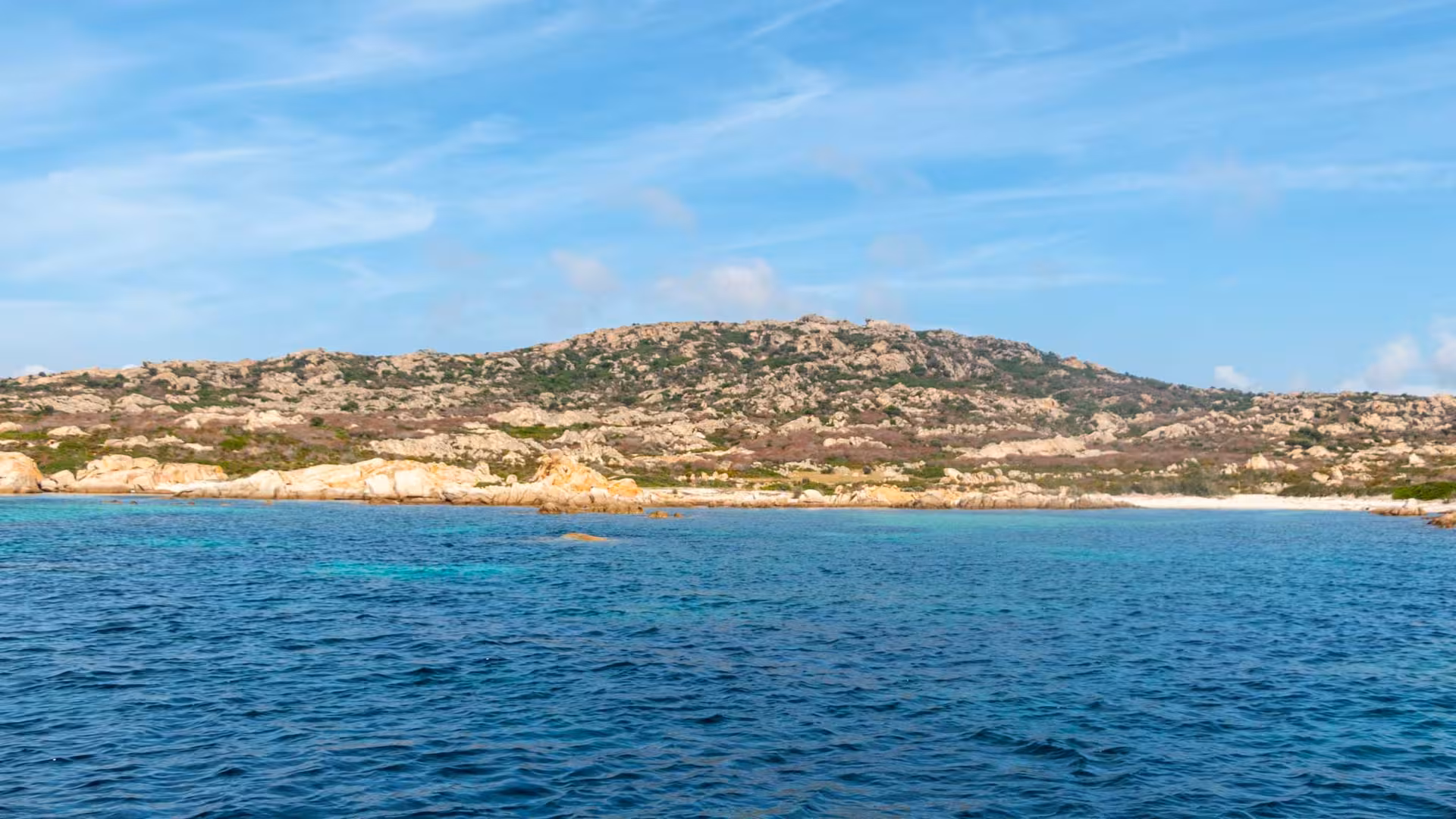Stunning coastal landscape of Asinara, showcasing rugged hills and clear blue waters from a sailboat tour.