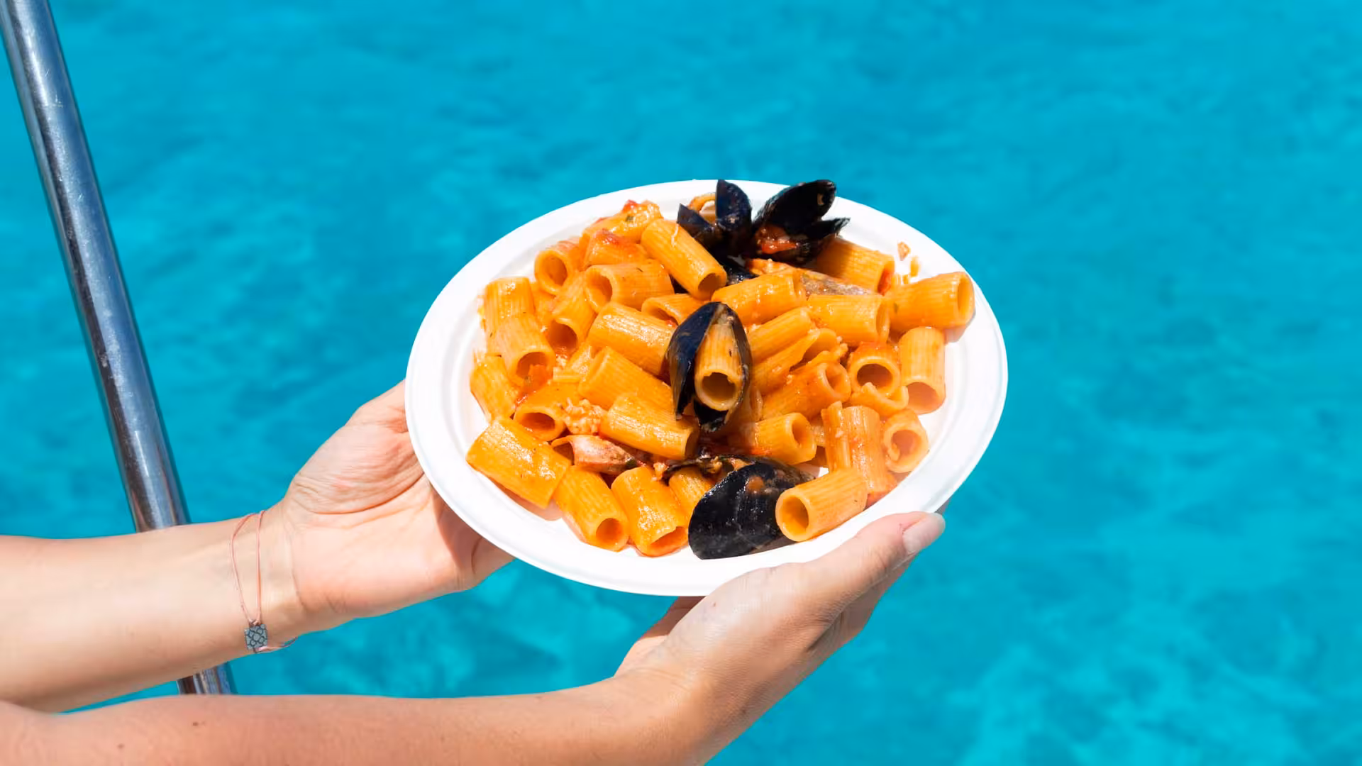 Savor delicious seafood pasta on a sailboat with crystal-clear waters on Asinara tour from Stintino.