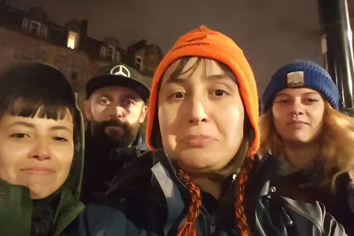 Group of four friends on a nighttime ghost walking tour in a city street