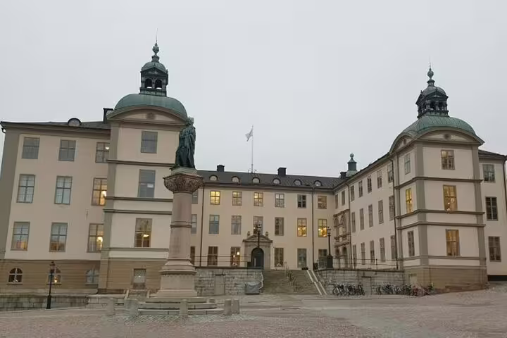 Historic Stockholm palace courtyard with green domed towers and statue on overcast day