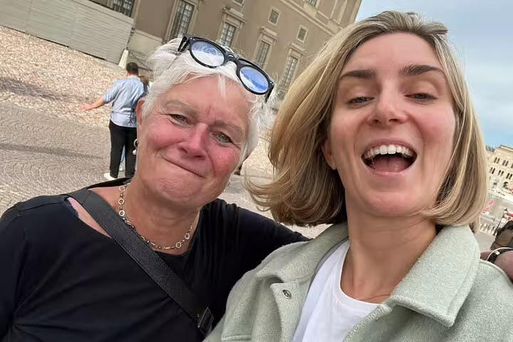 Two women smiling on a Stockholm walking tour near a historic palace square