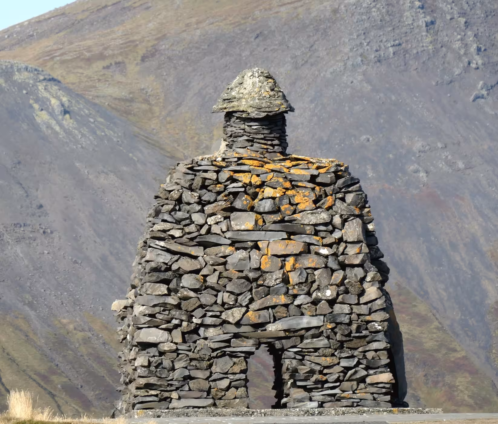 Large stone cairn sculpture shaped like a human figure with mountains in the background, Snaefellsnes Peninsula, Iceland