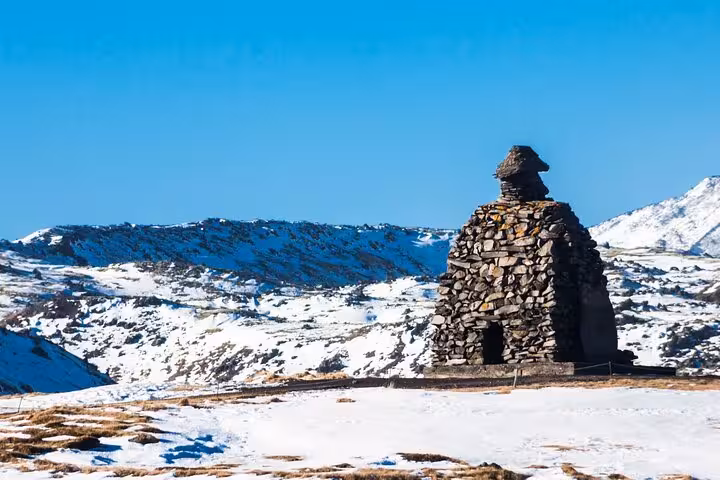 Stone cairn sculpture on snowy Snaefellsnes Peninsula with mountain backdrop in West Iceland