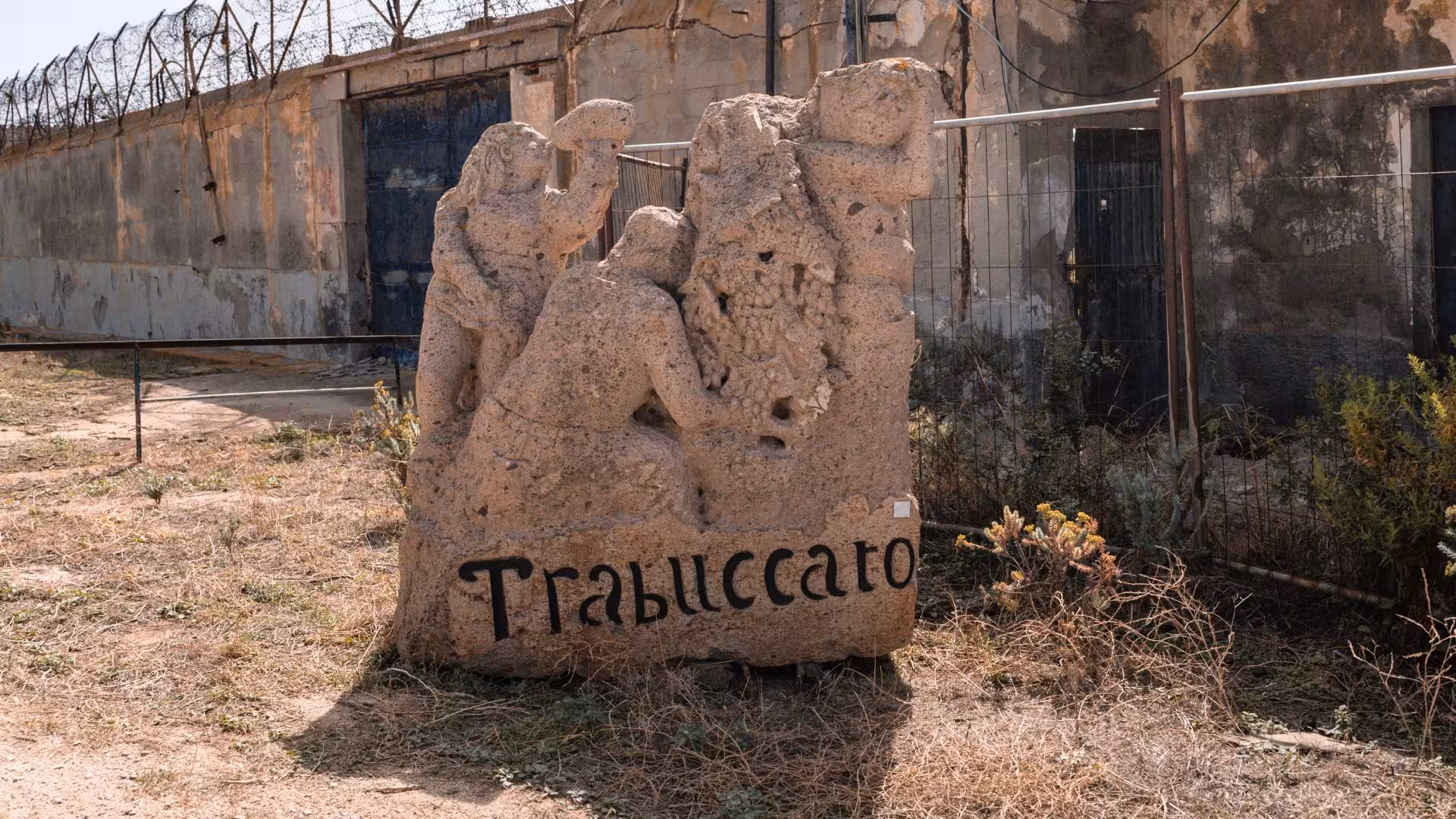 Stone sculpture with figures at former prison on Asinara Island, showcasing unique historical and cultural heritage.