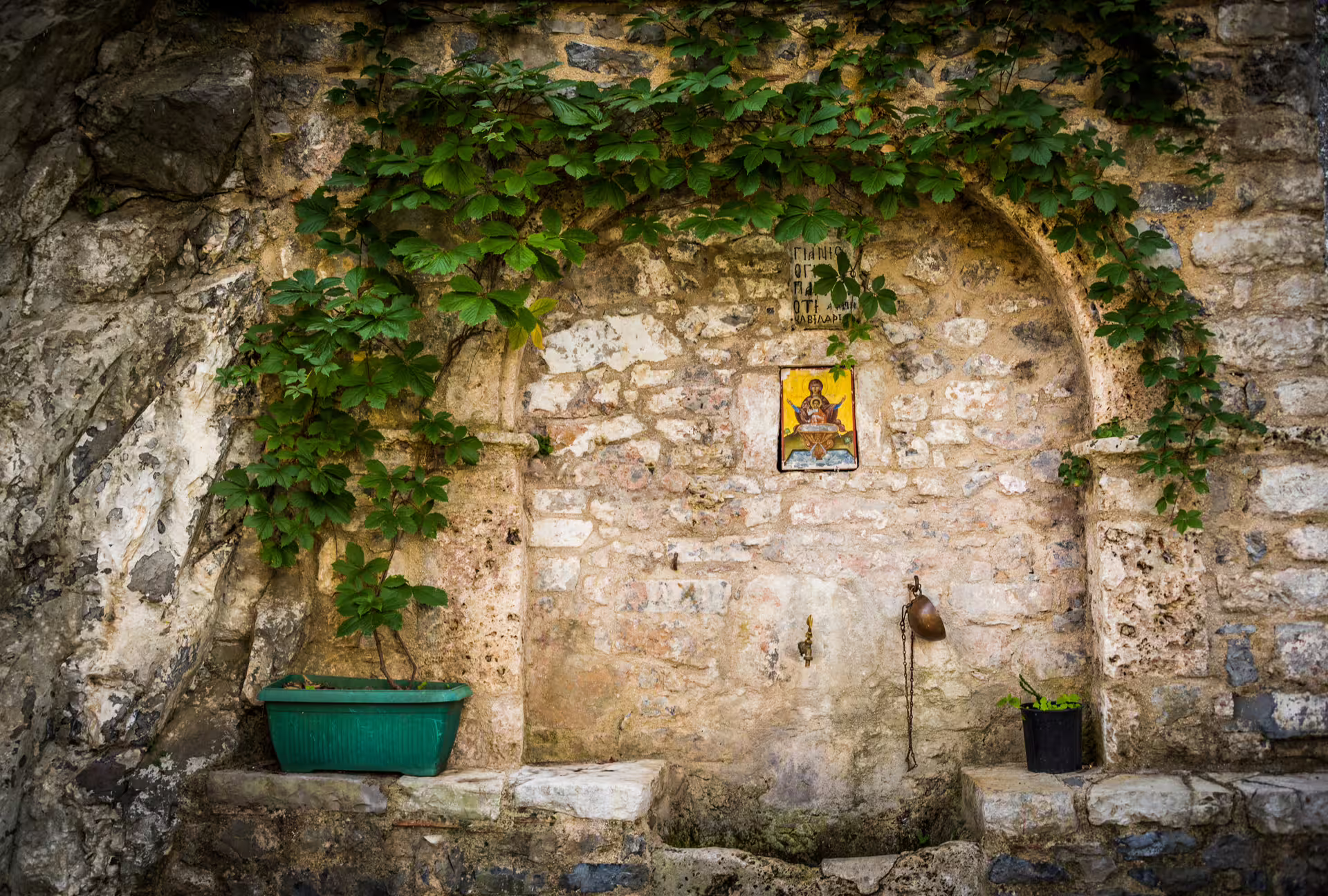 Stone spring with ivy and icon near Lousios Gorge trail, a scenic stop on the Arcadia guided hiking tour