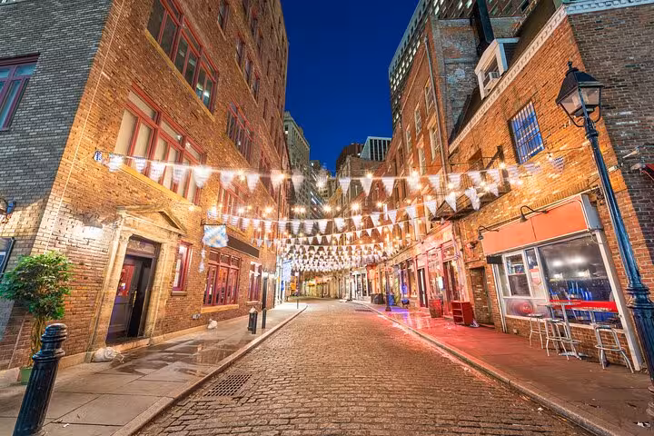 Cobblestone street with string lights and brick buildings in Lower Manhattan NYC at night