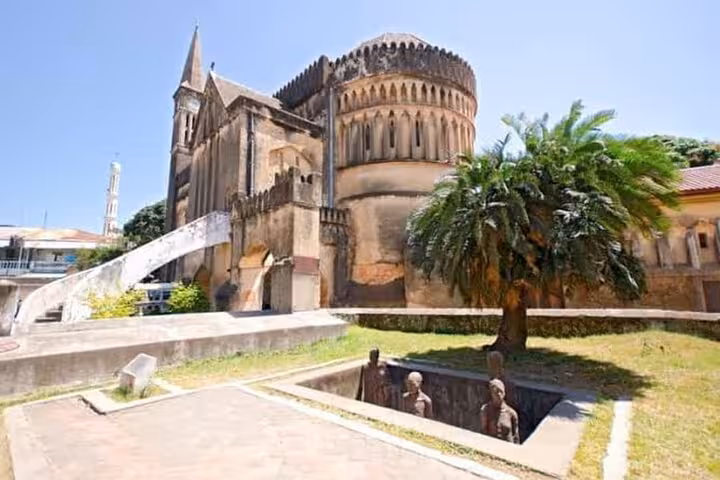 Old Anglican Cathedral in Stone Town surrounded by greenery, highlighting Zanzibar's rich historical architecture.
