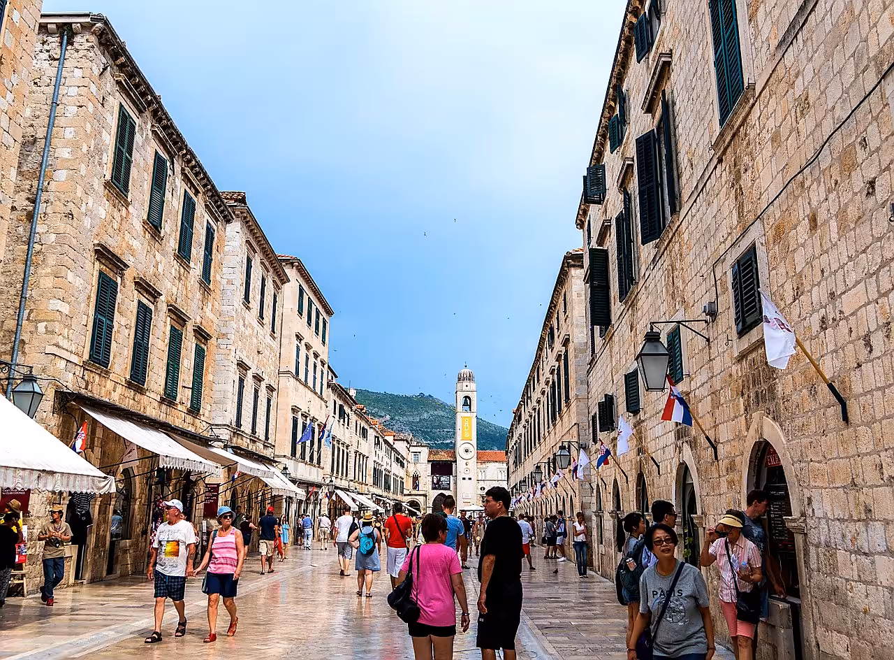 Crowds walking Stradun in Dubrovnik Old Town under blue sky, popular stop on Split to Dubrovnik day tour