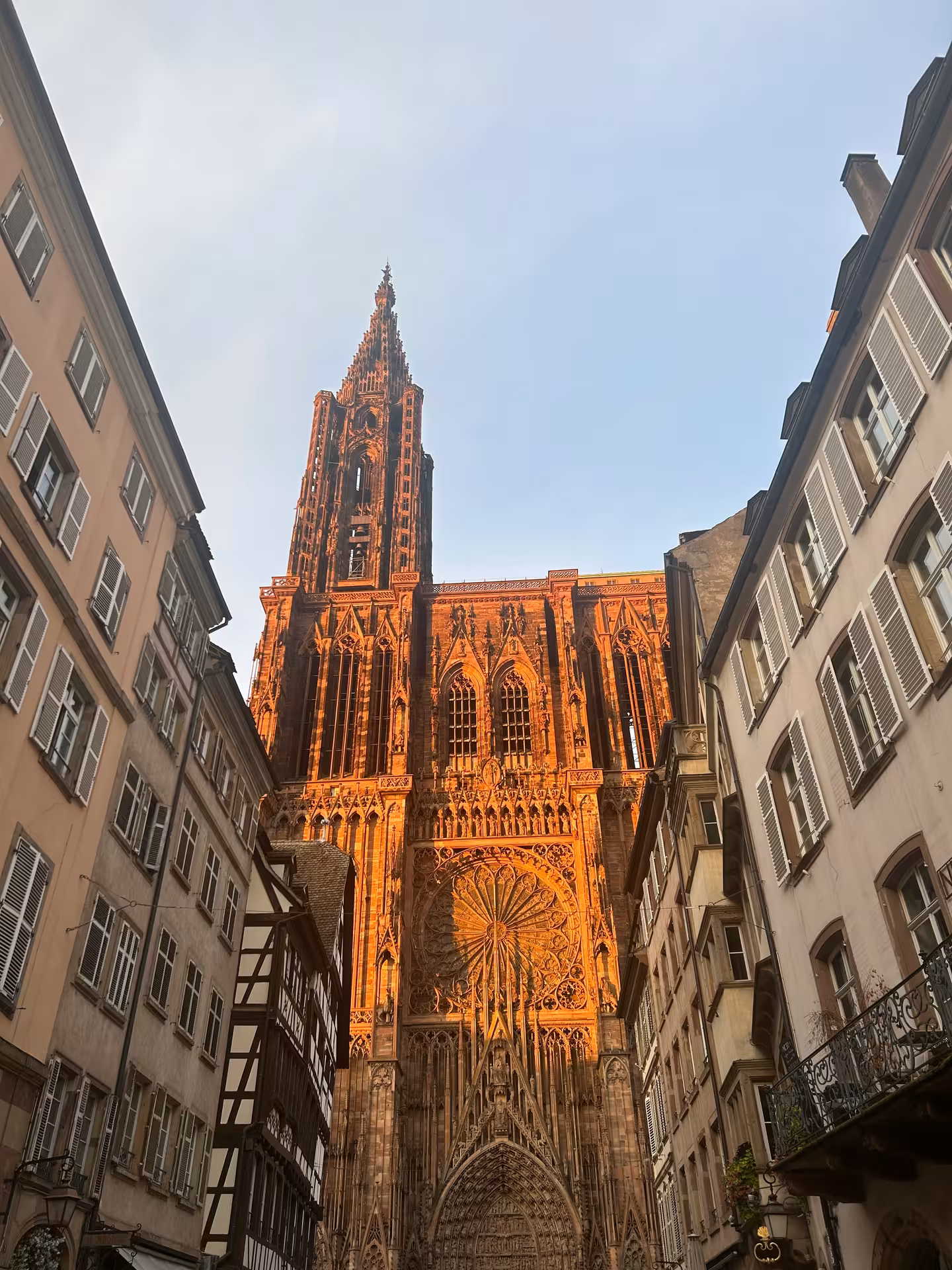 Strasbourg Cathedral gothic facade glowing orange at sunset viewed from narrow old town street