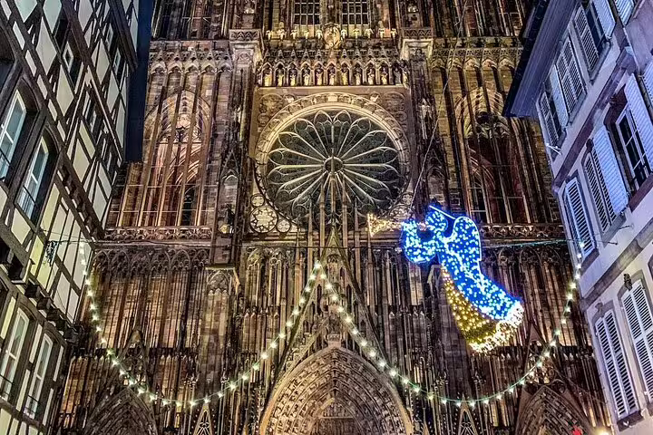 Strasbourg Cathedral facade illuminated at night with Christmas angel light decoration and string lights