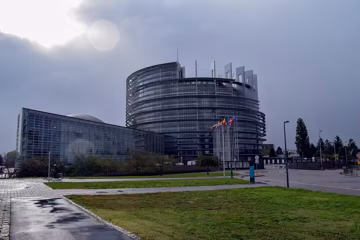 European Parliament building in Strasbourg with flags on a cloudy day