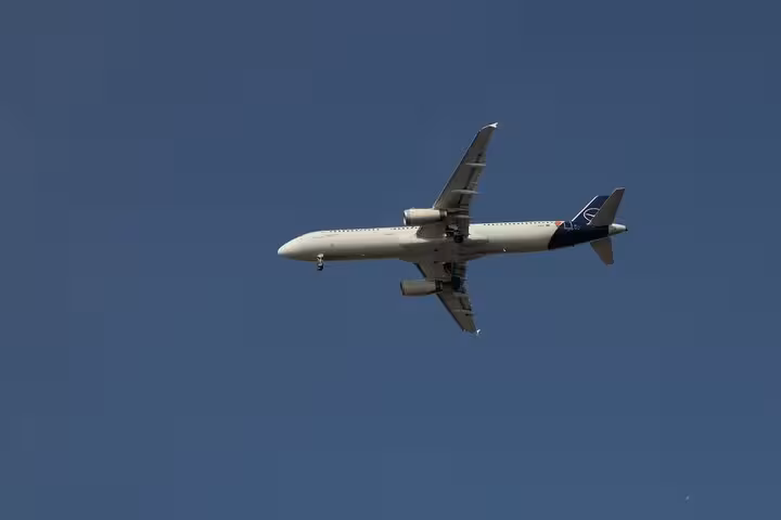 Commercial airplane flying over Strasbourg en route to Frankfurt under clear blue sky