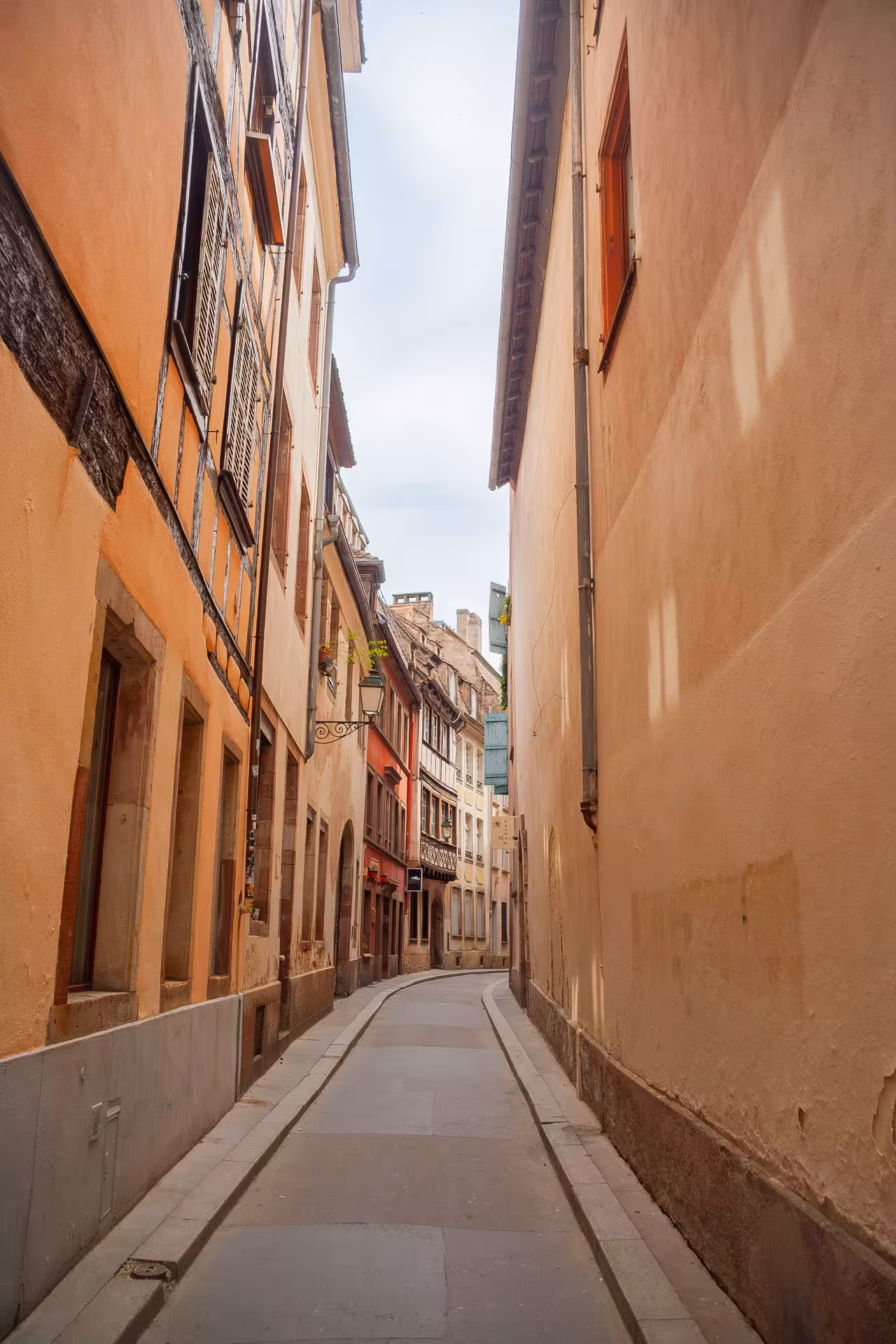 Narrow cobblestone alley flanked by warm-toned historic buildings in old Strasbourg