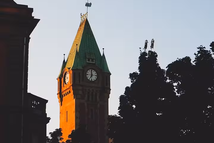 Historic clock tower with green copper spire glowing in golden sunset light in Strasbourg