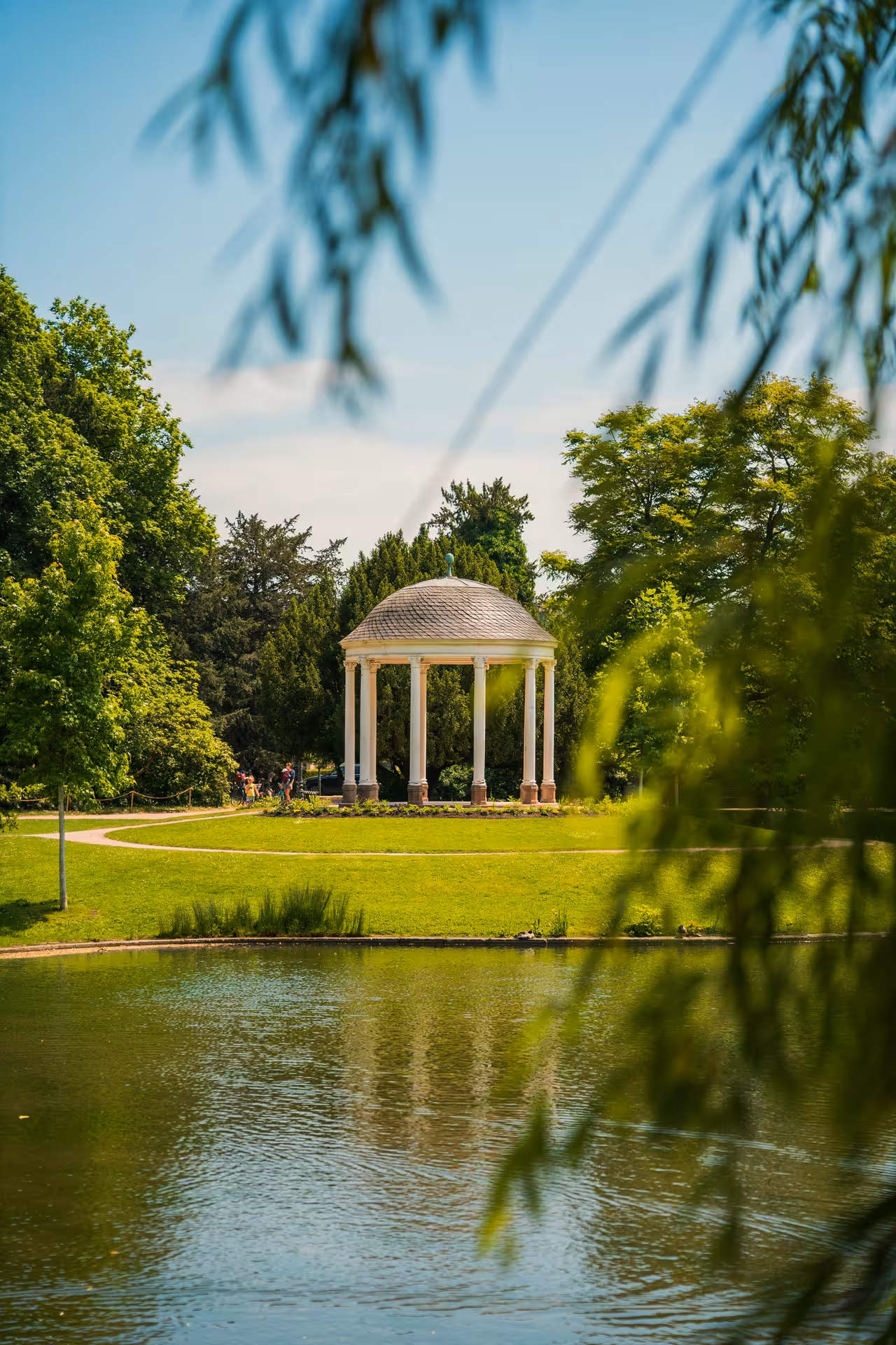 Classical domed rotunda pavilion reflected in a tranquil pond in a Strasbourg park