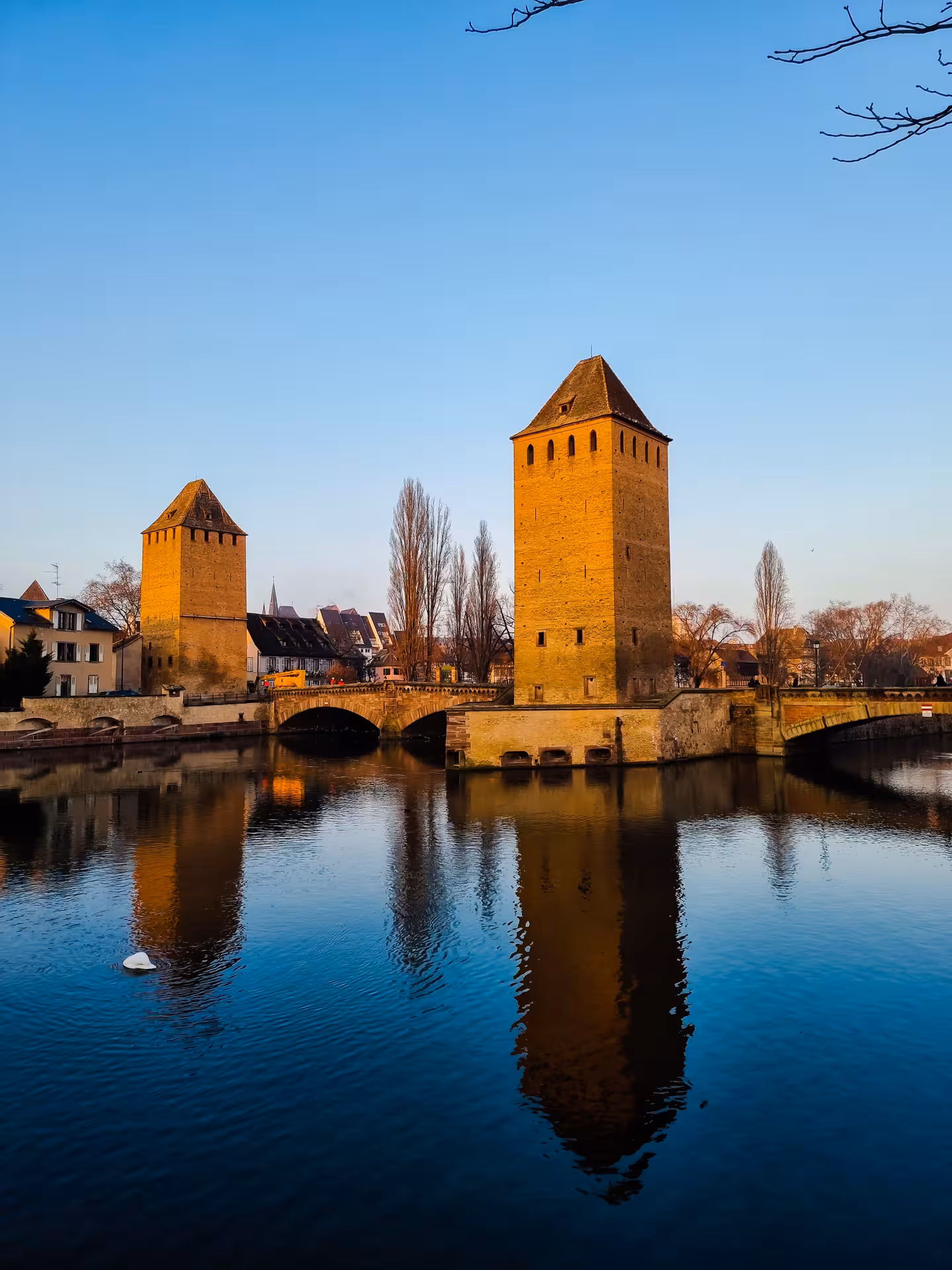 Medieval towers of Ponts Couverts reflected in the Ill River in Strasbourg, France at golden hour