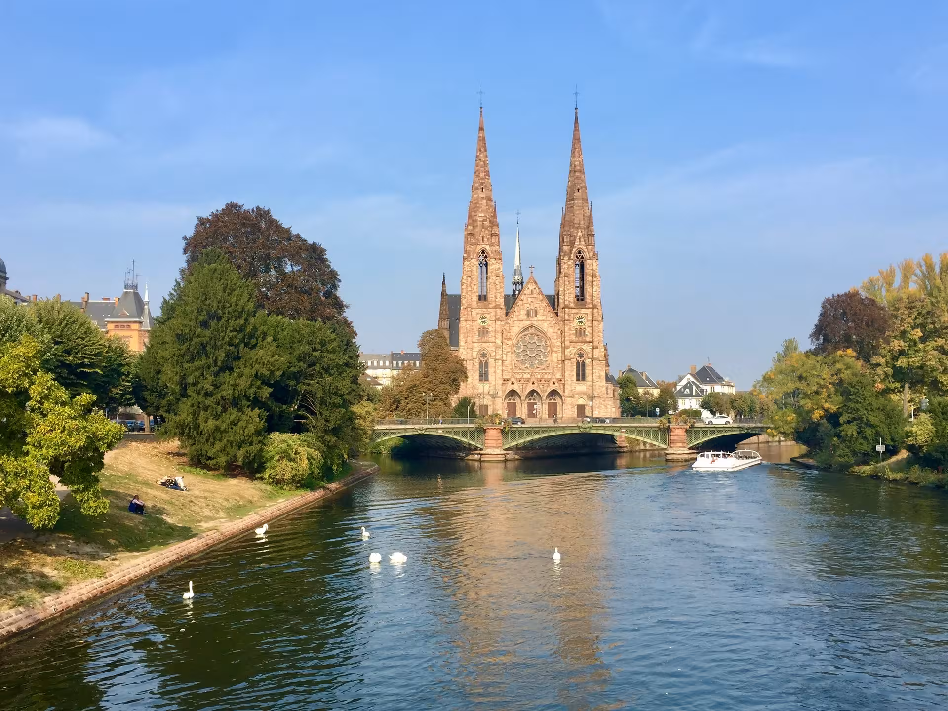 St. Paul's Church twin spires overlooking the Ill River with swans in Strasbourg, France
