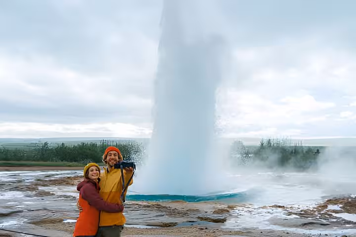 Couple posing in front of Strokkur geyser eruption on Golden Circle tour from Reykjavik