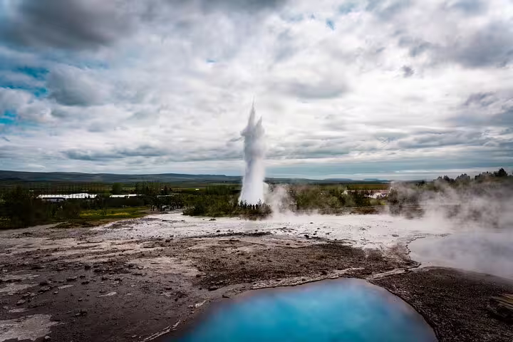 Strokkur geyser erupting on Iceland's Golden Circle with blue hot spring in foreground