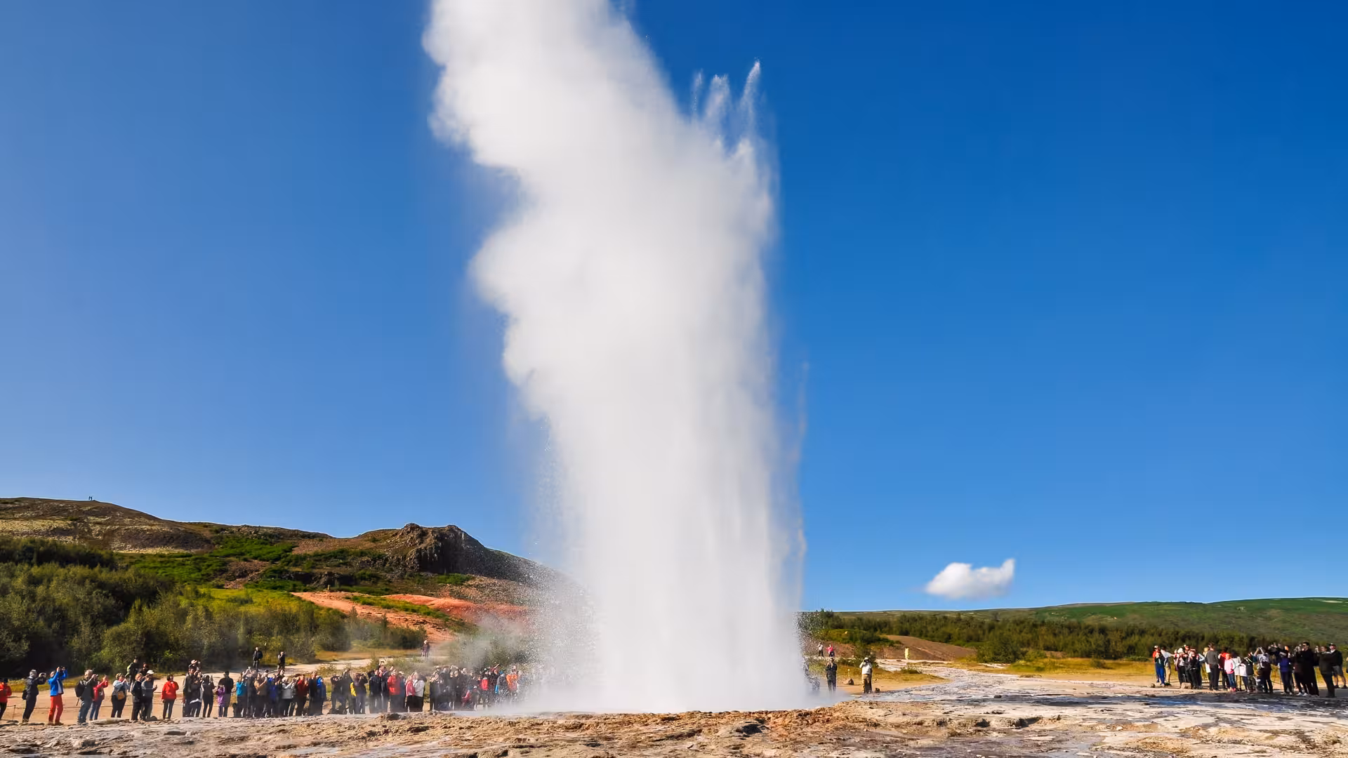 Strokkur geyser erupting on Iceland's Golden Circle with tourists watching nearby
