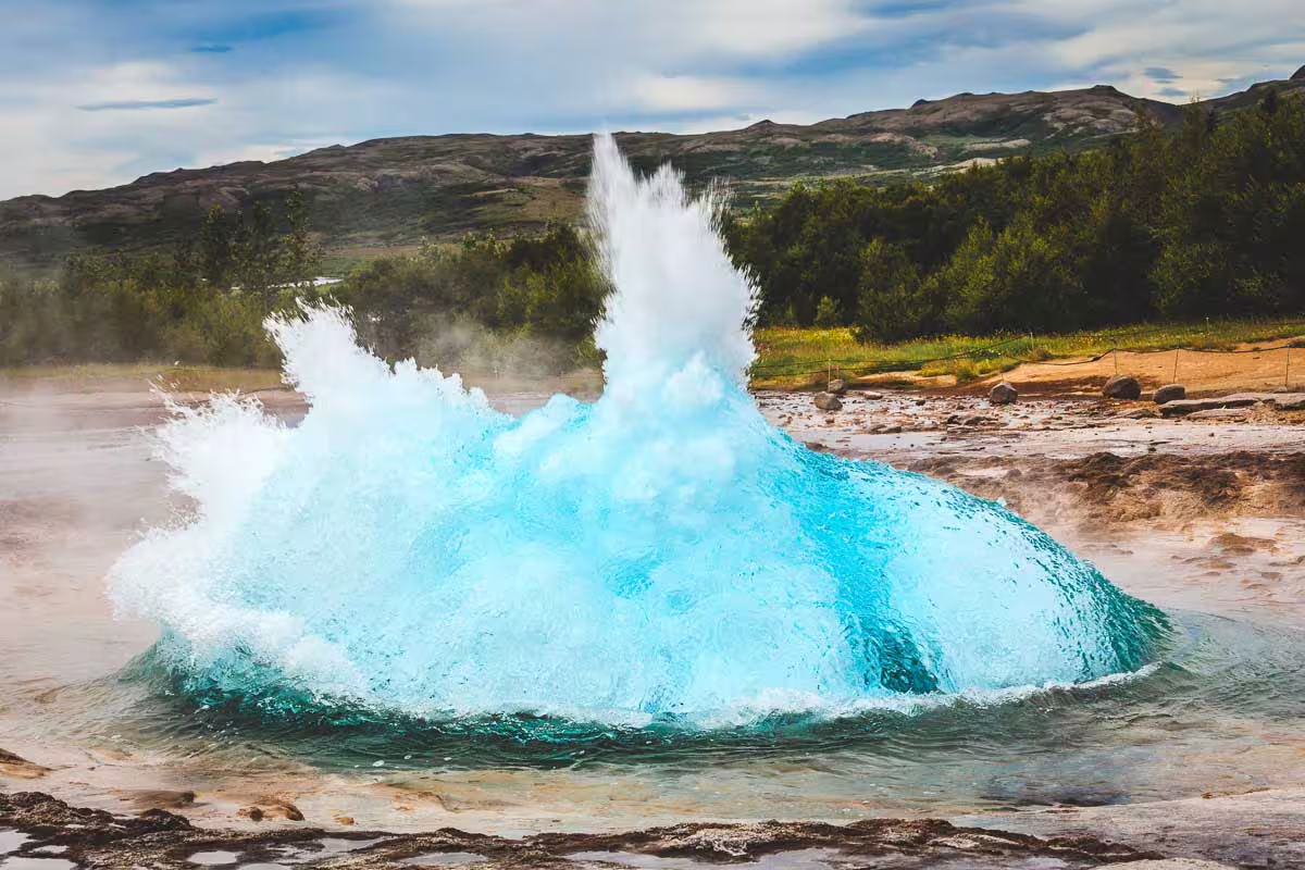 Strokkur geyser erupting with vivid turquoise water dome on Iceland's Golden Circle route