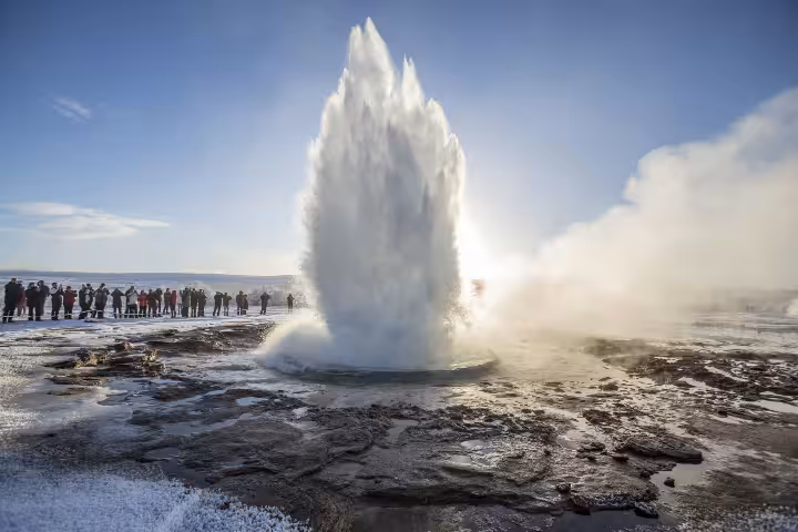 Strokkur geyser erupting on Iceland's Golden Circle with tourists watching in winter landscape