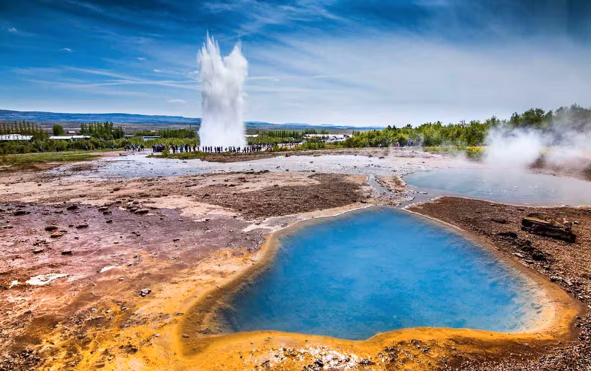 Strokkur geyser erupting with blue hot spring pool in Iceland's Golden Circle geothermal area