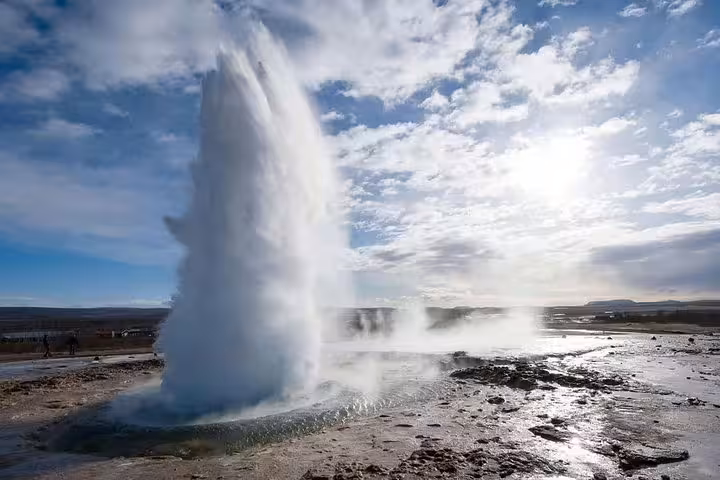 Strokkur geyser erupting on Iceland's Golden Circle with steam and water shooting high into cloudy sky