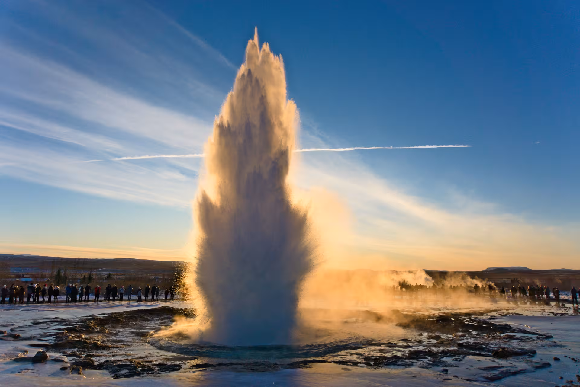 Strokkur geyser erupting on Iceland's Golden Circle with tourists watching at golden hour