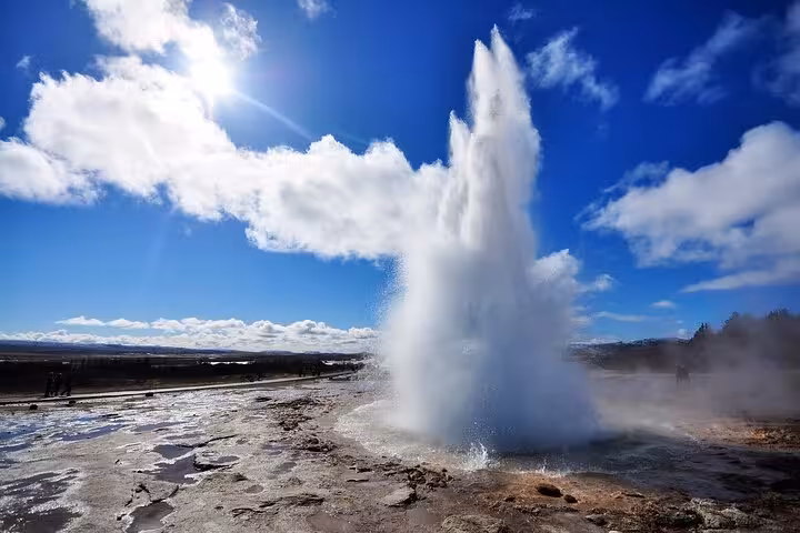 Strokkur geyser erupting on Iceland's Golden Circle route under a bright blue sky