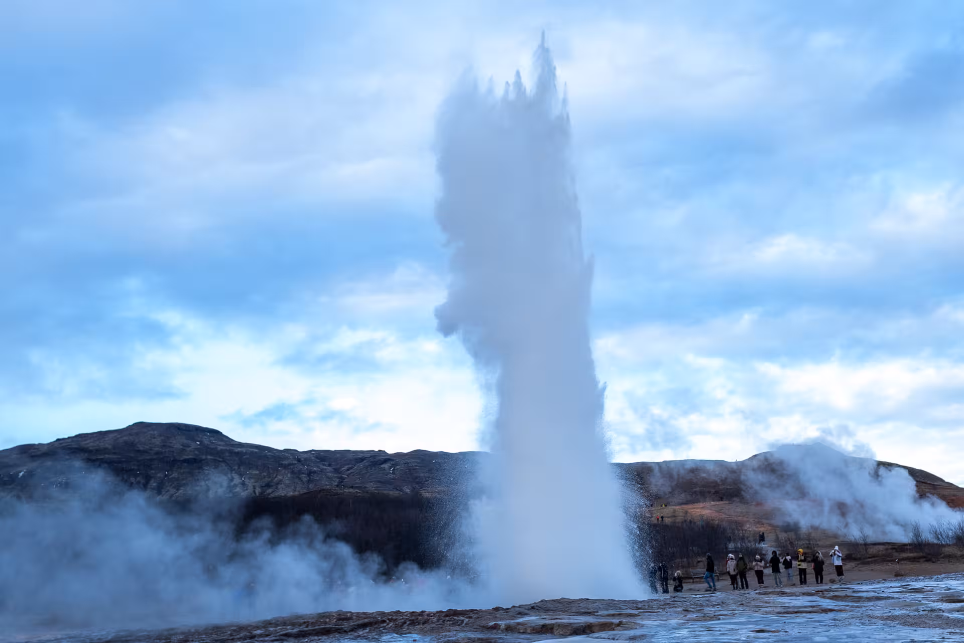 Strokkur geyser erupting on Iceland's Golden Circle with tourists watching nearby