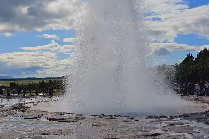 Strokkur geyser erupting on Iceland's Golden Circle with tourists watching nearby