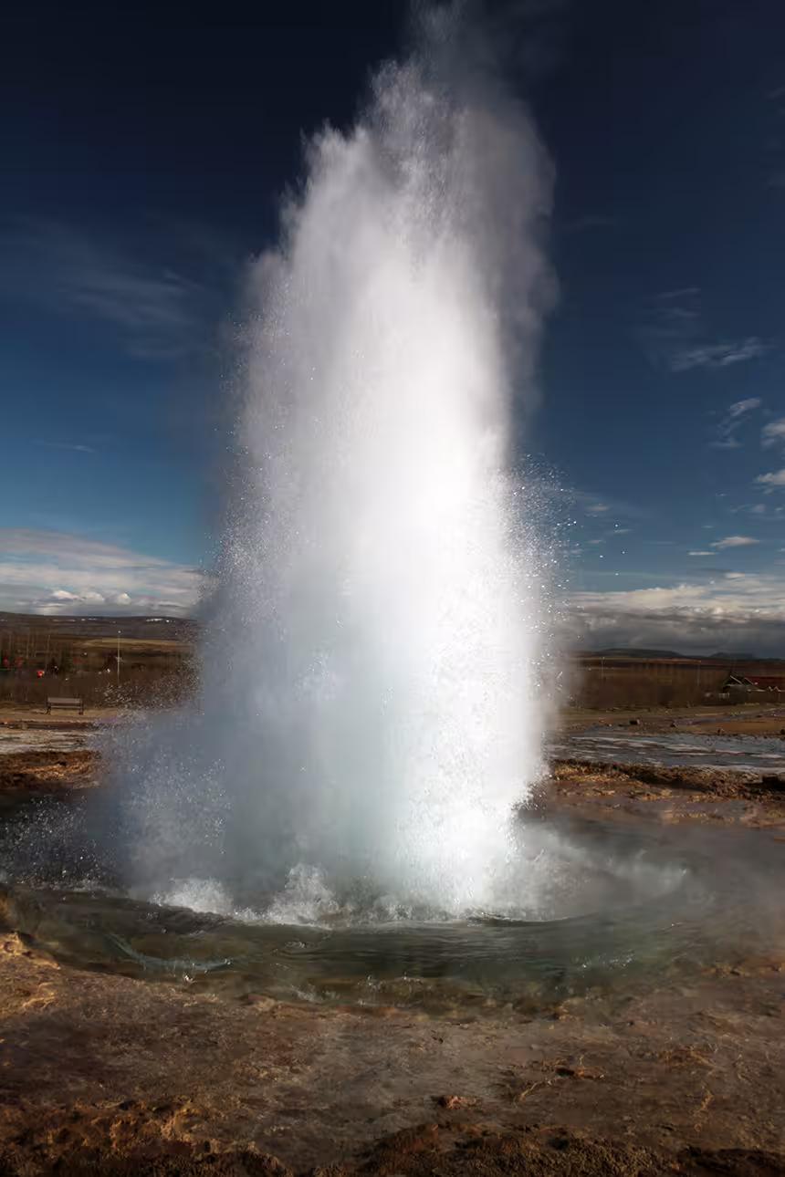 Strokkur geyser erupting on Iceland's Golden Circle with steam shooting high into blue sky