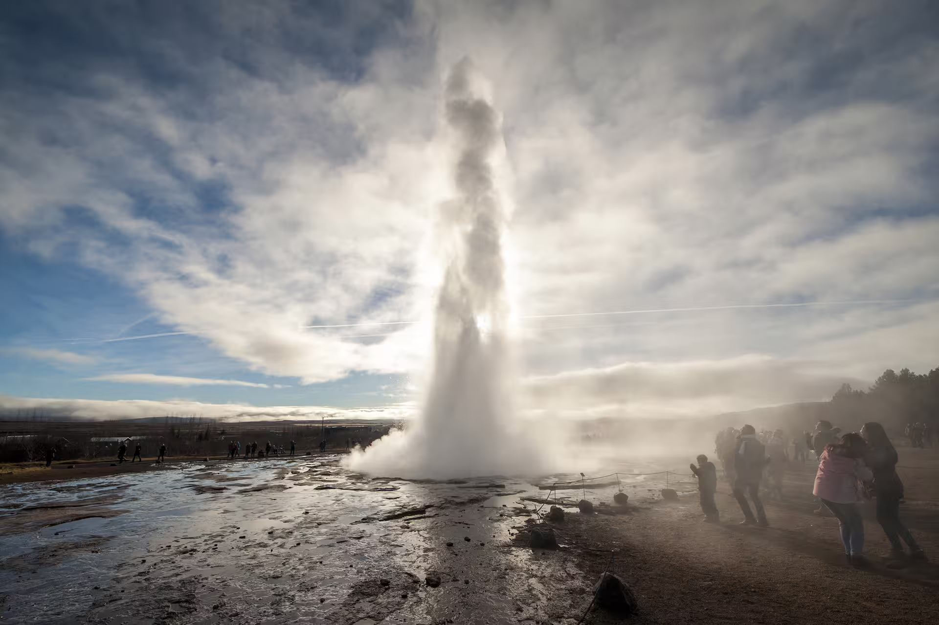 Strokkur geyser erupting on Iceland's Golden Circle with tourists watching steam and water shoot skyward