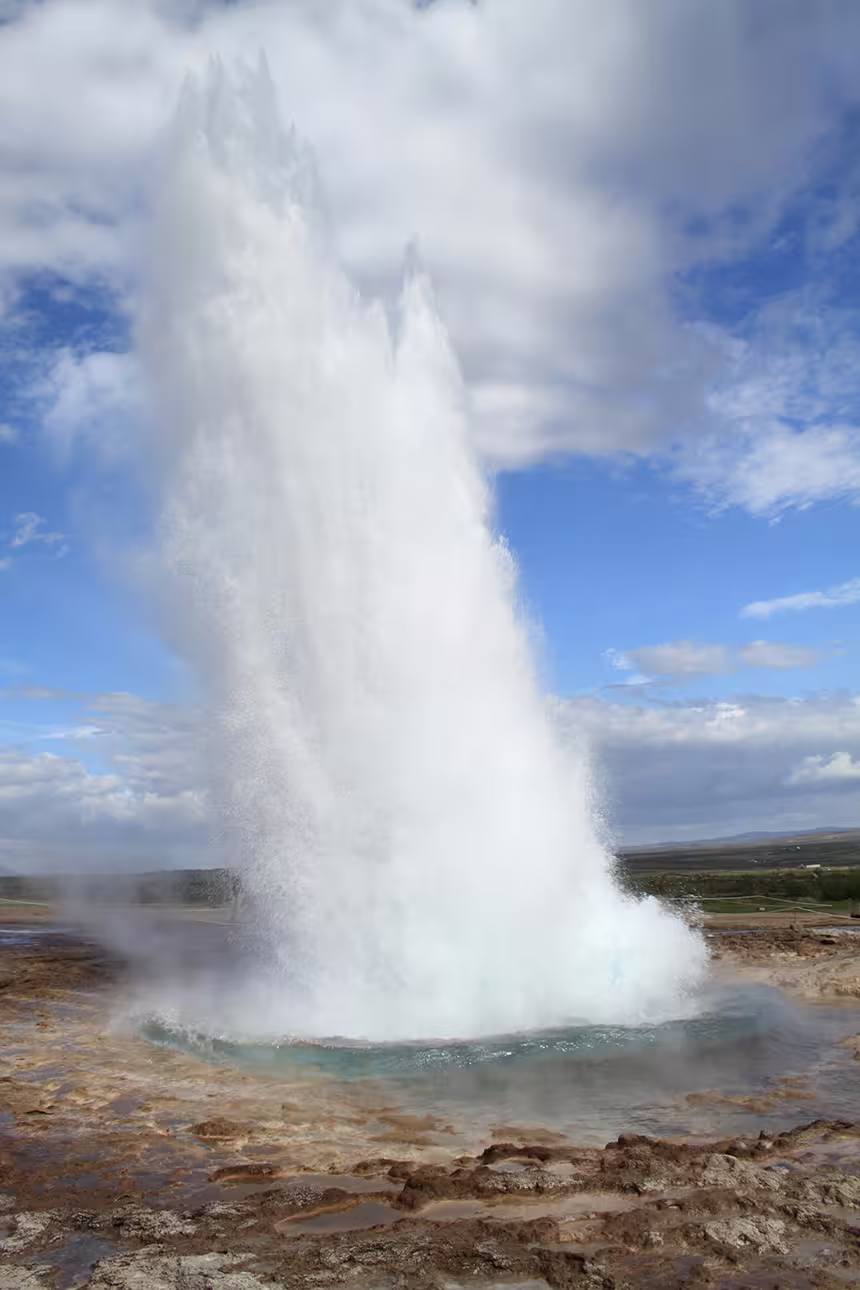 Strokkur geyser erupting on Iceland's Golden Circle with steaming water shooting high into blue sky