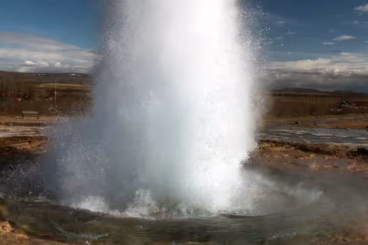 Strokkur geyser erupting on Iceland's Golden Circle with blue sky backdrop