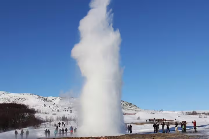 Strokkur geyser erupting on Iceland's Golden Circle with tourists watching in snowy winter landscape