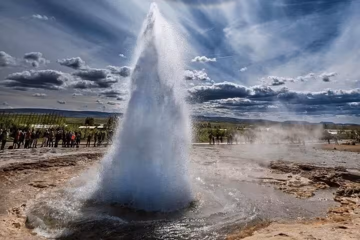 Strokkur geyser erupting on Iceland's Golden Circle with tourists watching in background