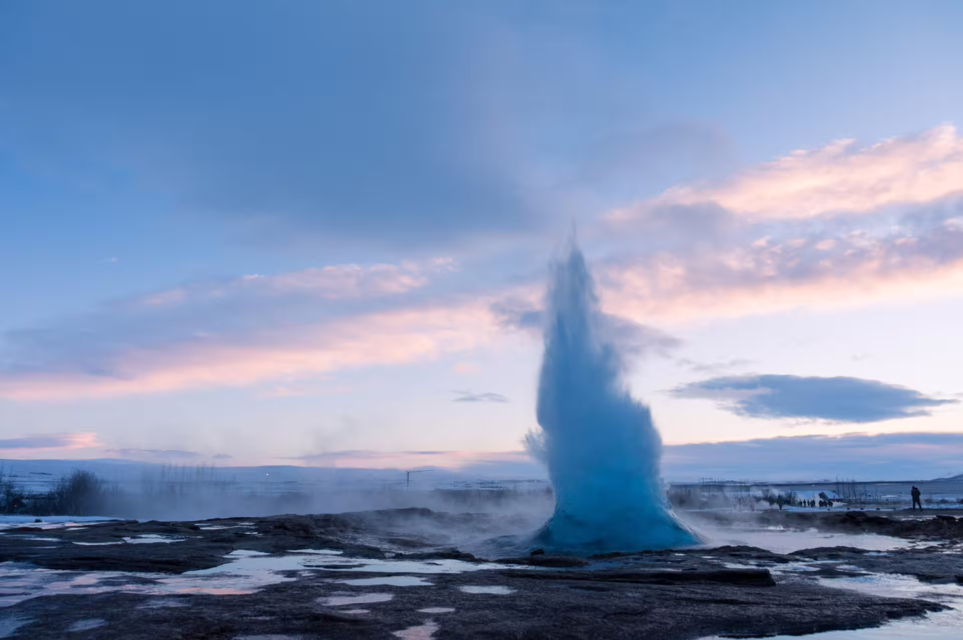 Strokkur geyser erupting blue water column at twilight on Iceland's Golden Circle route