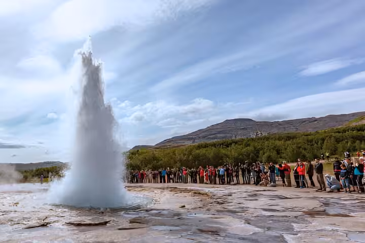 Strokkur geyser erupting on Iceland's Golden Circle with tourists watching from a safe distance