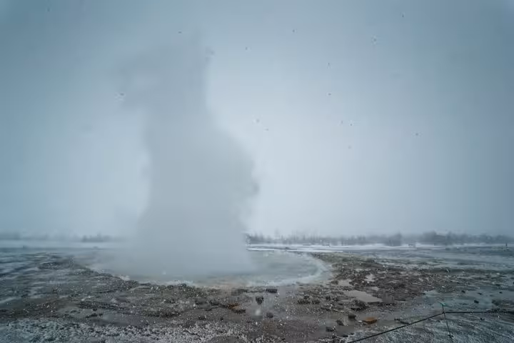 Strokkur geyser erupting steam into misty winter sky on Iceland Golden Circle Super Jeep tour