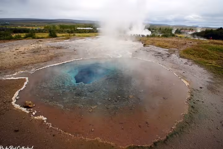 Strokkur geyser pool with vivid blue water and steam rising, Golden Circle Iceland