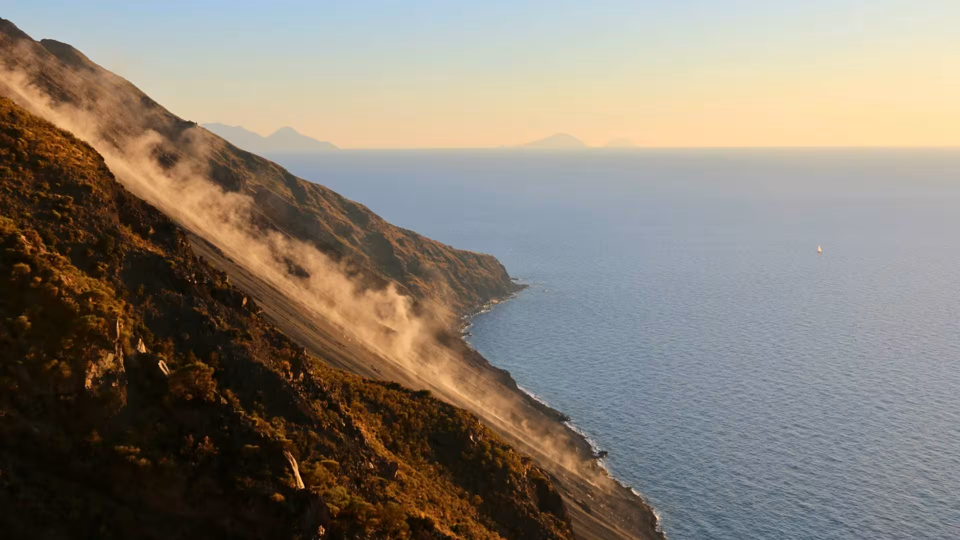 Dramatic volcanic landscape with smoke rising from the slopes of Stromboli at sunset.