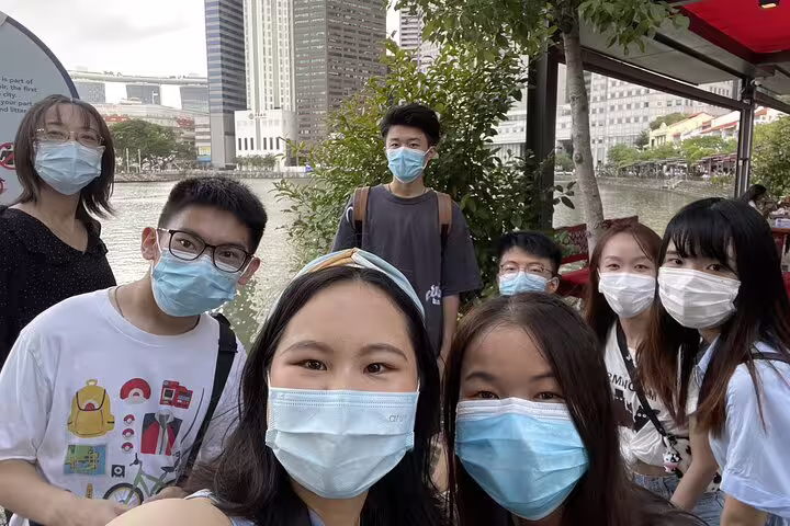 Group of students wearing face masks taking a selfie along Singapore's historic Clarke Quay waterway