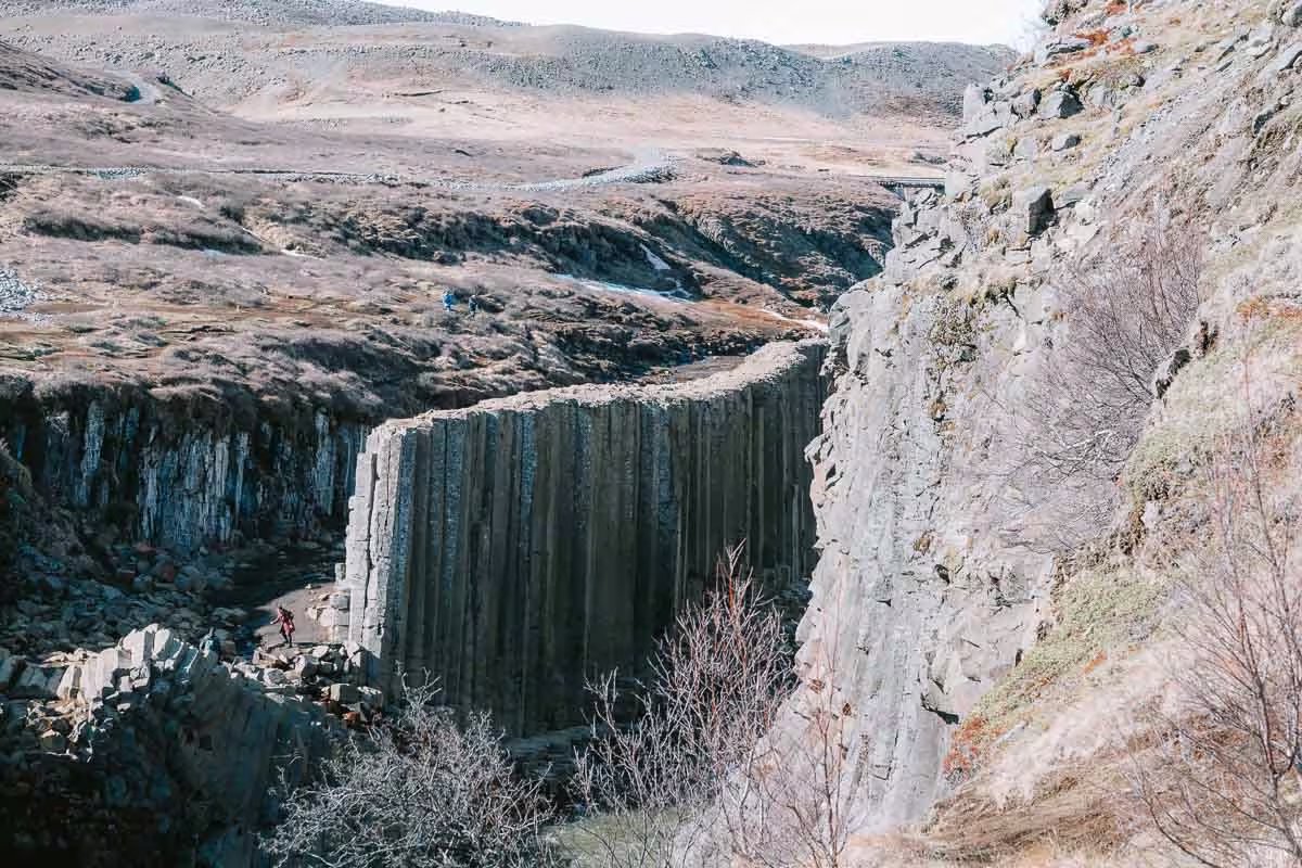 Studlagil Canyon basalt column walls with hikers exploring the narrow gorge in East Iceland