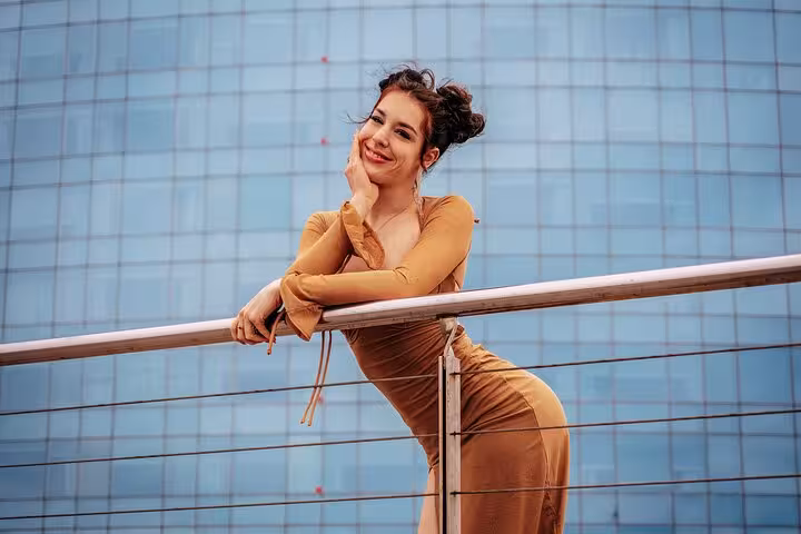 Stylish traveler posing by a railing against a modern glass building during a private Barcelona photoshoot with a pro.