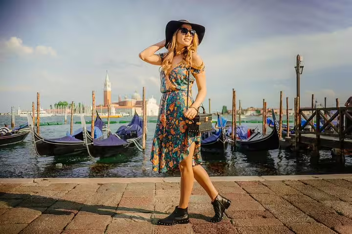 Stylish woman posing by the gondolas in Venice on a private photo shoot walking tour.