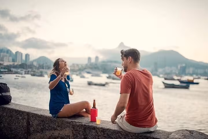 Two locals share drinks at sunset by the waterfront, capturing the essence of a happy hour near Sugarloaf Mountain.